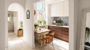 Une cuisine lumineuse avec des meubles en bois, une table à manger avec des chaises et une fenêtre agrémentée de plantes.