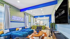A modern living room with a sectional sofa, a coffee table, and a TV mounted on the wall. - Urban Haven Indy | Hot Tub + Game Room (Indianapolis)