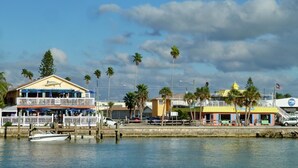 A waterfront property with a dock, a boat, and a building with a balcony overlooking the water. - Madeira Norte 406 - Premier (Madeira Beach)