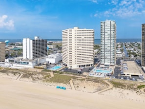A coastal cityscape with high-rise buildings, a beach, and a parking area. - Oceanfront Condo With Pool - Steps To The Beach (Ocean City)