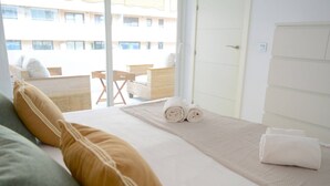 Ein Hotelzimmer mit Bett, Kissen, einem gerollten Handtuch und Blick auf den Balkon.