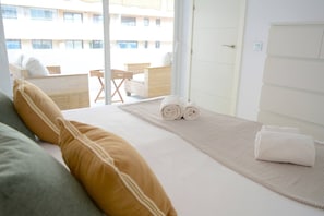 Ein Hotelzimmer mit Bett, Kissen, einem gerollten Handtuch und Blick auf den Balkon.