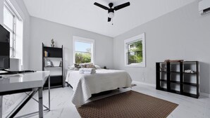 Un dormitorio con cama, escritorio, estantería y ventilador de techo.
