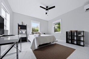 Ein Schlafzimmer mit einem Bett, einem Schreibtisch, einem Bücherregal und einem Deckenventilator.