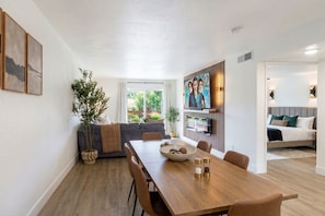 A modern dining area with a wooden table, chairs, and a bowl of fruit.