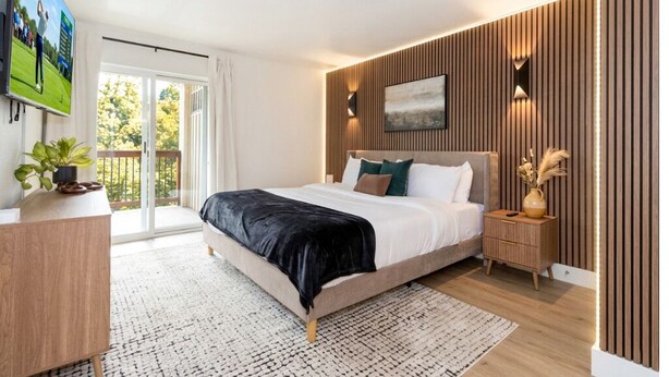 A modern bedroom with a bed, bedside table, and a TV. - Pet-Friendly Branson Condo Sleeps 6~ Walk to Landing, Pools, Resort & Gym access (Branson)