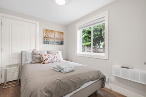Ein Schlafzimmer mit einem Bett, einem Fenster mit Blick, einem Heizkörper und einer Tür.