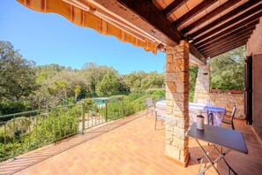 A terrace with stone pillars, a table with chairs, and a view of trees and a pool. - Lou Christalou - Avec Piscine privée (Carcès)