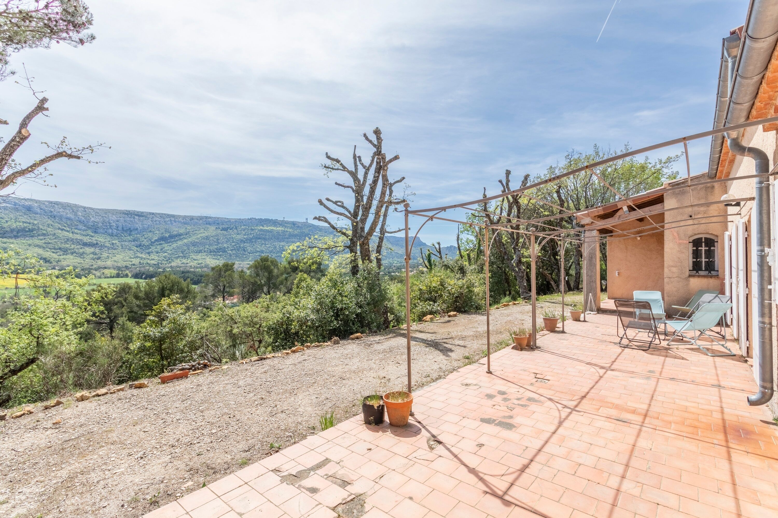 Une terrasse offrant une vue sur un paysage vallonné, un bâtiment à l’extérieur en briques et un ciel dégagé.