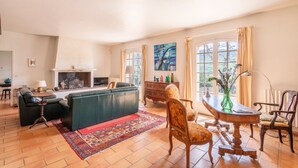 Ein Wohnzimmer mit Kamin, einer Couch, einem Couchtisch und einem Esstisch mit Stühlen.