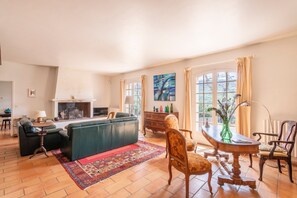 Ein Wohnzimmer mit Kamin, einer Couch, einem Couchtisch und einem Esstisch mit Stühlen.