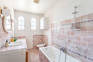 Un baño con bañera, lavabo, espejo y ducha.