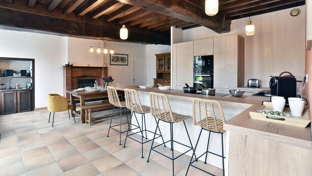 Eine moderne Küche mit Holzboden, Barhocker und Esstisch.