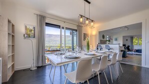A modern dining area with a large table set for four, a pendant light, and a view of the outdoors.