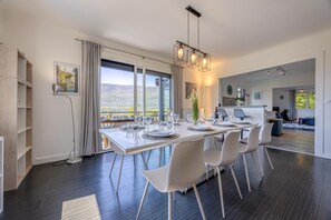 A modern dining area with a large table set for four, a pendant light, and a view of the outdoors.