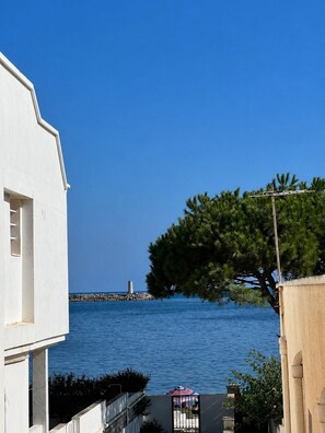 Une vue sur la côte, avec un bâtiment blanc, un arbre et un phare situé au loin.