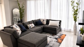 Un salon moderne avec un canapé d’angle, une table basse et des coussins décoratifs.