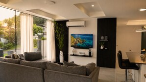 Un salon moderne comprenant un canapé, un téléviseur à écran plat et un coin repas avec une table et des chaises.