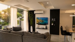 A modern living room with a sofa, a flat-screen TV, and a dining area with a table and chairs. - -20% Maravillas 1BR Condo near Beach and Port-of-Spain (With Pool) (Port of Spain)