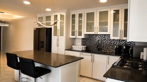 A modern kitchen with white cabinets, a black countertop, and a built-in stove.