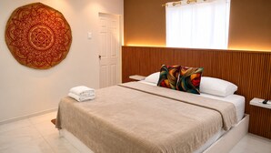 Une chambre d’hôtel avec un lit, une table de chevet, une décoration murale et une fenêtre avec des rideaux.