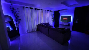 A modern living room with a sofa, a television displaying 'NETFLIX', and a plant.