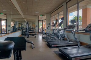 Ein Fitnessstudio mit Laufbändern, Kraftgeräten und einer Trainingsbank.