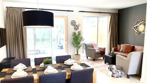 Ein modernes Wohnzimmer mit Esstisch für vier Personen, einer Couch, einem Couchtisch und einer Topfpflanze.
