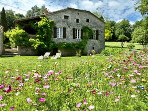 A stone house with a garden full of flowers and a clear sky. - Large house with swimming pool and green park (Sainte-Colombe-de-Villeneuve)