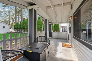 Eine überdachte Veranda mit Tisch und Stühlen, Blick auf den Garten und ein Haus im Hintergrund.