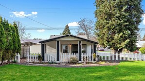 A single-story house with a front porch, a picket fence, and a well-maintained lawn. - Charming CDA Cottage · Walk to Downtown & the Lake (Coeur d'Alene)