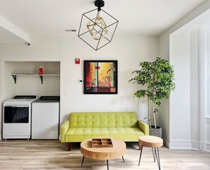 A modern living room with a green sofa, a wooden coffee table, and a potted plant. - Ramblei near Drexel Park: 6-Bedroom Unit B (Philadelphia)