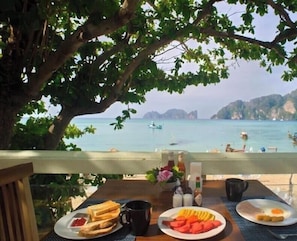 A table with breakfast items and a view of a coastal area with boats and cliffs. - Bay View Resort Koh Phi Phi (Ko Phi Phi)
