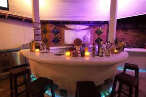 A bar area with a round table, bar stools, and a variety of bottles. - Bay View Resort Koh Phi Phi (Ko Phi Phi)