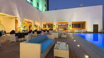 A rooftop pool area with outdoor seating and a dining setup.