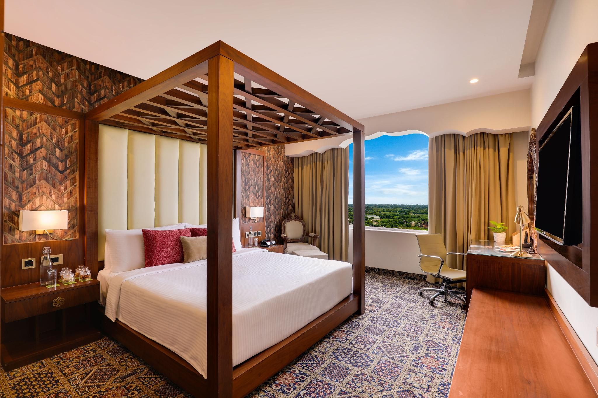 A four-poster bed with a view, a desk with a chair, and a TV in a hotel room.