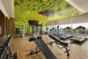 A gym with exercise equipment, large windows, and a green ceiling. - Saura Hotel Agra A Club Mahindra (Agra)