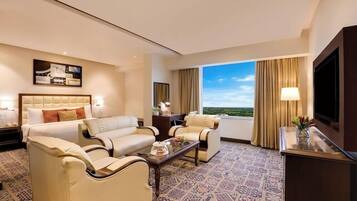 A hotel room with a large bed, two sofas, a coffee table, and a TV.