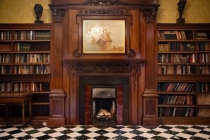 Una biblioteca con chimenea, estanterías y piso a cuadros.