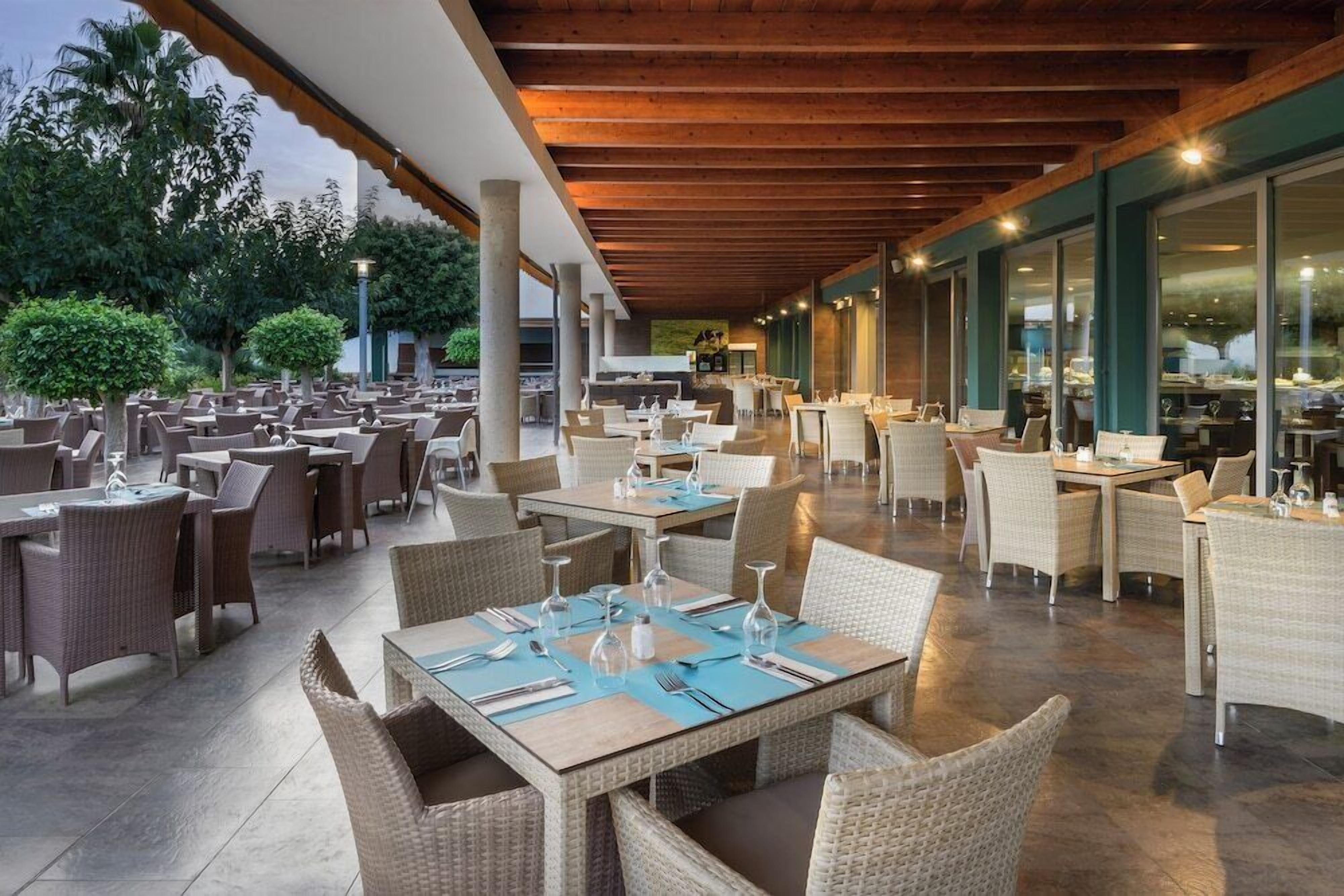 An outdoor dining area with wicker furniture and tables set for guests.