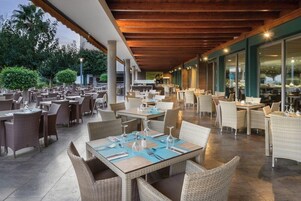 Un área de comedor al aire libre con mobiliario de mimbre y mesas dispuestas para los huéspedes.