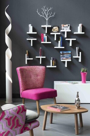 Ein modernes Wohnzimmer mit einem einzigartigen Bücherregal, einem gemusterten Sessel und einem runden Couchtisch.