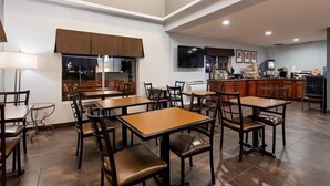 A dining area with tables and chairs, a kitchen area with appliances, and a television on the wall. - Surestay Hotel By Best Western Blythe (Blythe)