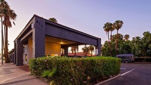 A modern building with a flat roof, a covered entrance, and a parking area with a vehicle. - Surestay Hotel By Best Western Blythe (Blythe)