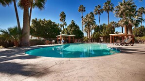 A swimming pool with lounge chairs and a covered seating area, surrounded by palm trees. - Surestay Hotel By Best Western Blythe (Blythe)
