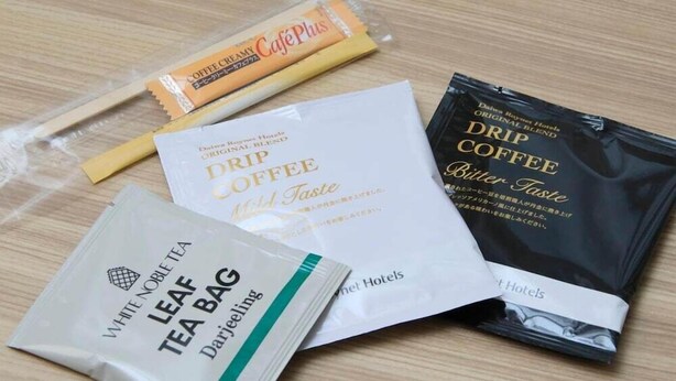 Variedad de productos de té y café, incluyendo una bolsita de té blanco noble, café de filtro y crema de café.