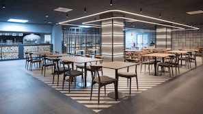 En moderne restaurant med et centralt siddeområde, en bar og udsigt over bybilledet.