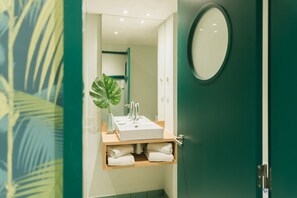 Ein Badezimmer mit Waschbecken, Spiegel und Pflanze.