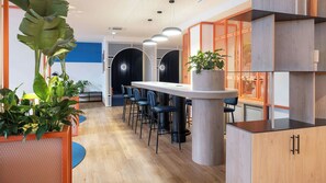 Et moderne interiør med en lang bar, siddepladser og potteplanter.