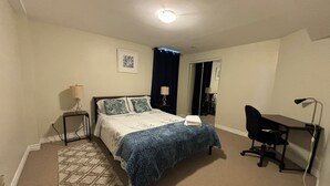 Hotellihuone, jossa on sänky, työpöytä, tuoli ja pieni matto.